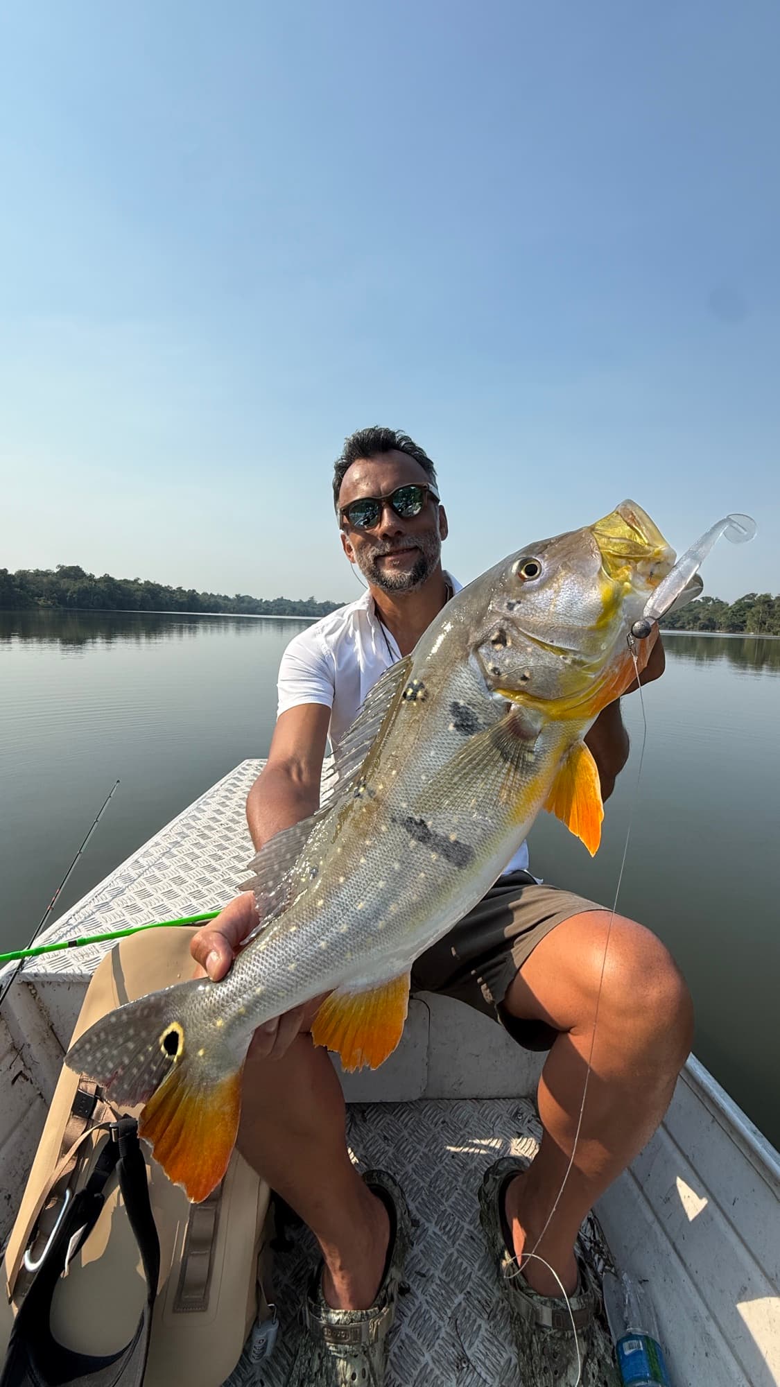 Pastor Eddy Nakazora holding a large peacock bass on a boat on the Amazon River