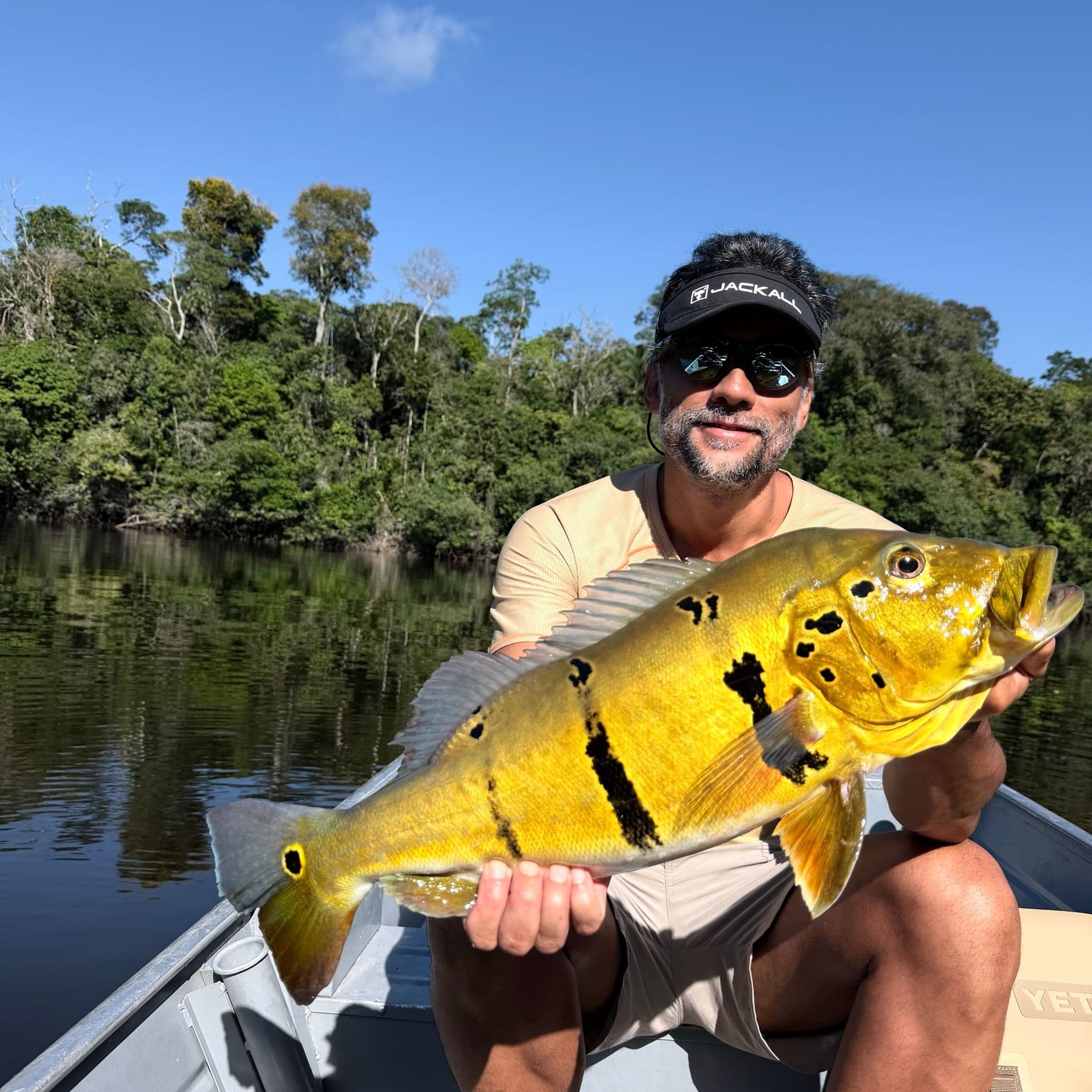 An angler holding a golden peacock bass on the Amazon River