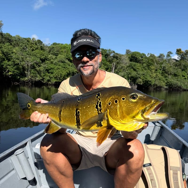 An angler with a peacock bass in an aluminum boat